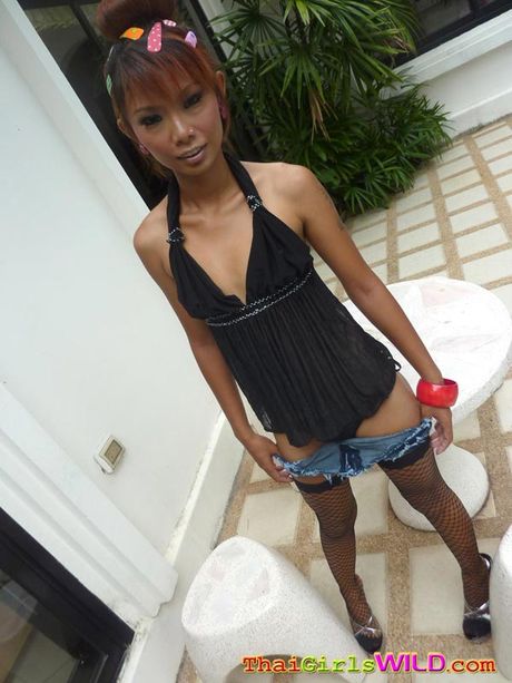 Skinny redhead Thai slut Malai is outside and strips to show off her leggy body